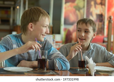 Two Cute Boys Drinking Coke In Cafe