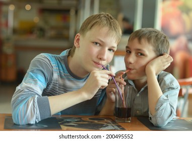 Two Cute Boys Drinking Coke In Cafe