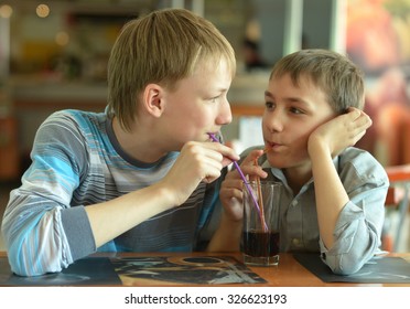 Two Cute Boys Drinking Coke In Cafe