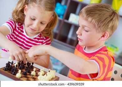 Two Cute Children Playing Chess At Home