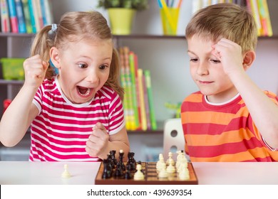 Two Cute Children Playing Chess At Home