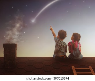 Two Cute Children Sit On The Roof And Look At The Stars. Boy And Girl Make A Wish By Seeing A Shooting Star.