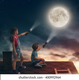Two cute children sit on the roof and look at the moon.