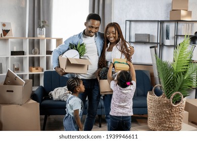 Two cute daughters helping their afro american parents packing boxes for relocation. Young happy family feeling excited about moving to new house.