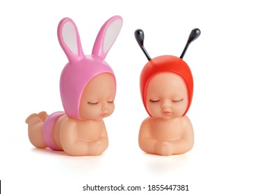 Two cute dolls in beetle and bunny costumes with closed eyes on awhite isolated background.Collection of toys.Soft focus