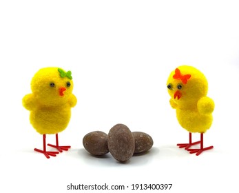 Two Cute Easter Chicks Looking At Small Chocolate Easter Eggs On A Plain Background. No People. Copy Space..