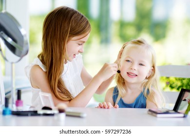 Two cute funny sisters applying make-up on sunny summer day at home. Adorable girls playing with their mommy`s cosmetic accessories.  - Shutterstock ID 597297236