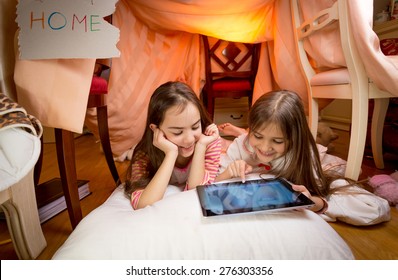 Two Cute Girls Lying On Floor At Bedroom And Playing On Digital Tablet