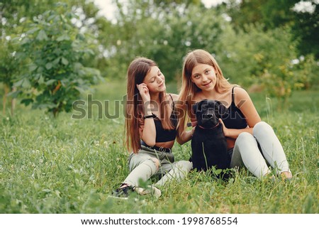 Two cute girls in a summer park with a dog