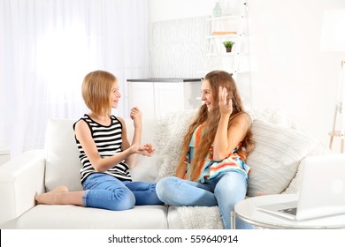 Two Cute Girls Talking On Sofa