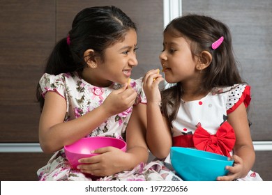 Two Cute Indian Girls Eating Murukku. Asian Sibling Or Children Living Lifestyle At Home.