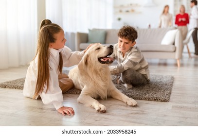 Two cute kids sitting on floor at home, petting golden retriever dog, their parents and granny on background. Multi generation family spending time together in living room - Powered by Shutterstock