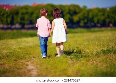 Two Cute Kids Walking Away On Summer Field