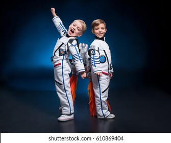 Two cute little boys in space suits standing back to back looking at camera
