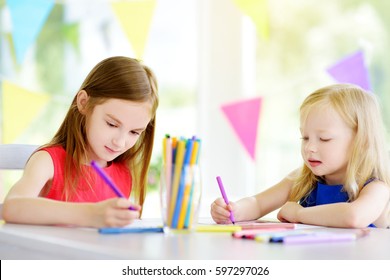 Two Cute Little Sisters Drawing With Colorful Pencils At A Daycare. Creative Kids Painting Together. Girls Doing Homework At Home. 