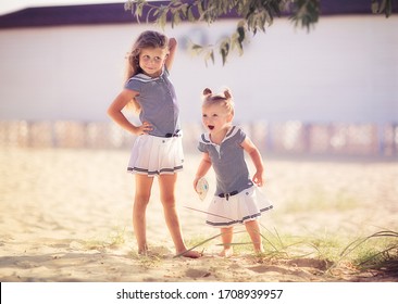 Two Cute Sisters In The Same Sea Dresses Eating An Ice Cream On The Beach