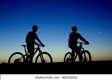 Two Cyclists On The Background Of Night Sky And Moon