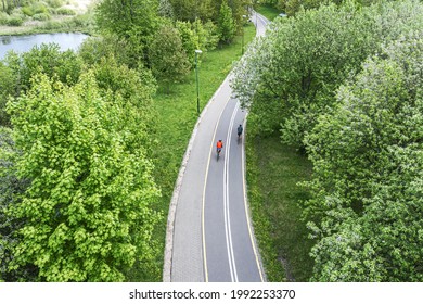 Two Cyclists Ride Bikes On Bicycle Path In City Park At Spring Day. Aerial Photography With Drone.