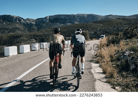 Two cyclists training on Vall d'Ebo pass.Cycling in the spanish mountains.Cyclists in helmets and cycling wear conquer Vall d'Ebo pass.Sport motivation.Cycling professional group ride.Beautiful view.