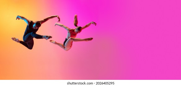 Two dancers, stylish sportive couple dancing contemporary dance on colorful gradient yellow pink background in neon light. Concept of art, creativity, movement, style and fashion, action. Flyer