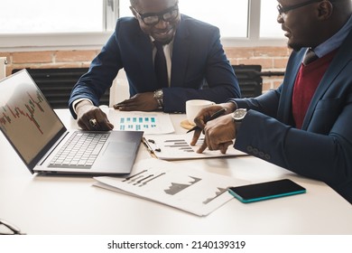 Two dark-skinned partners of an African American businessman at a meeting work on a laptop with a stock market trading terminal. Training in technical analysis and the study of economic indicators - Powered by Shutterstock