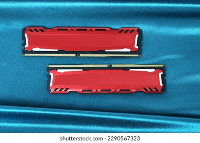 Two ddr4 ram memory modules with red metal diffusers on a shiny green cloth surface