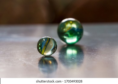 Two Decorative Colored Glass Balls With Bubbles Inside Reflecting In Icy Surface. Concept Of Similarity, Design Elements.