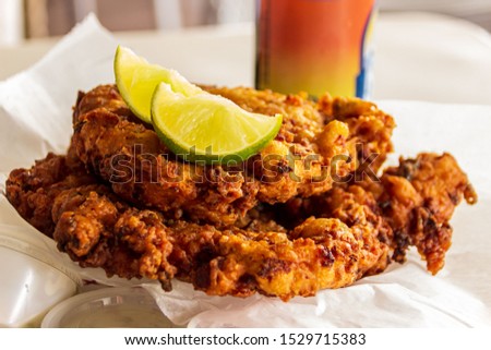 Two delicious conch fritters with sliced limes served as an appetizer.