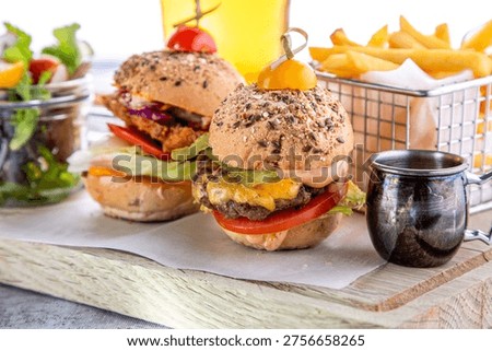 Two delicious mini sliders with beef patties, melted cheese, fresh tomatoes, and lettuce on seeded buns, served with french fries and a glass of beer.