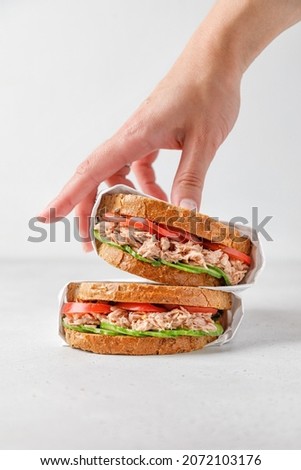 two delicious tuna sandwiches with tomato and cucumber in paper 