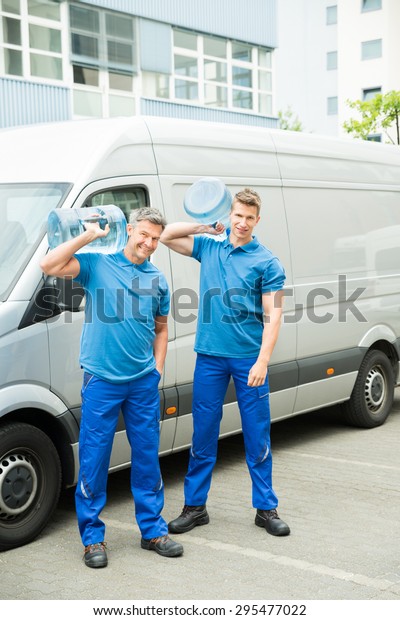 Two Delivery Men In Front Of Cargo Van Delivering\
Bottles Of Water