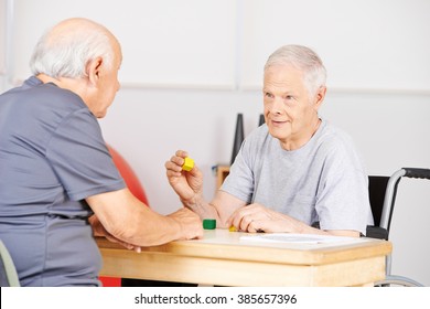 Two Demented Senior Men In Nursing Home Talking To Each Other And Playing With Building Bricks