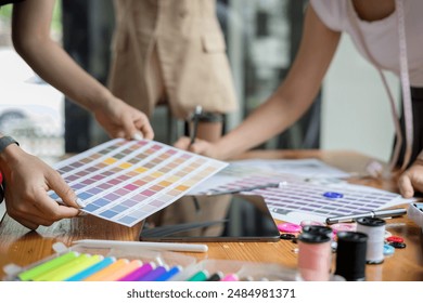 Two designer are working at a table with a color swatch chart and making notes. collaborative design or fashion project and creativity
