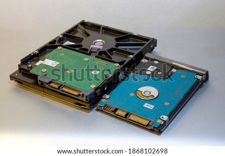 Two different size hard disk drive or hdd one is 3.5 inch and the other is 2.5 inch sata port connection  side by side with the green and blue board face up 