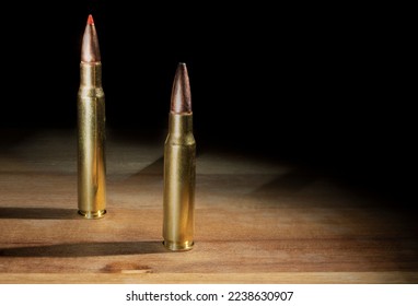 Two different sized 30 caliber caertridges on a wood table with copy space