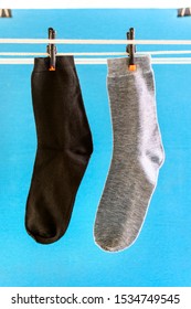 Two Different Socks On White Rope And Blue Background