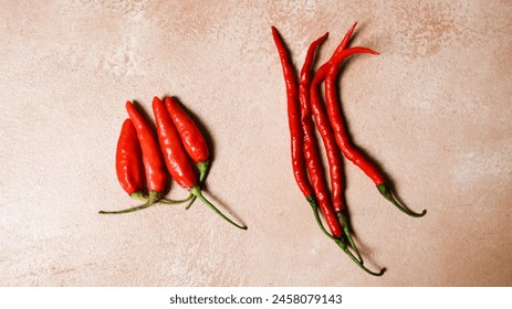 Two different types of red peppers are displayed side by side. The peppers are arranged in a way that they are not touching each other, and they are all pointing in different directions