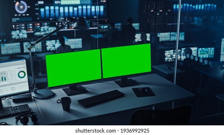 Two Digital Computer Screens With A Green Mock Up Chromakey In Modern Monitoring Office. Control Room With Specialists And Managers Sit In Front Of Computers.