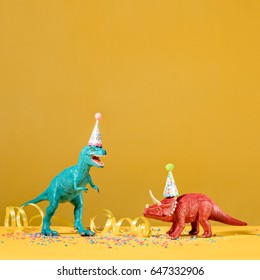 Two Dinosaurs With Birthday Hats Partying On A Yellow Background.