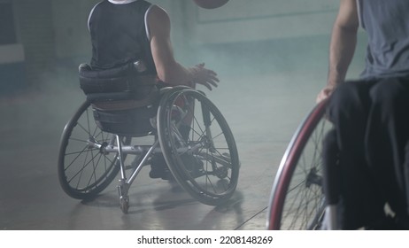 Two Disabled Athletes Playing Basketball. Handicapped Athlete In Wheelchair Passes Ball To Team Member