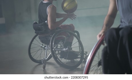 Two Disabled Athletes Playing Basketball.  Athlete In Wheelchair Passes Ball To Team Member