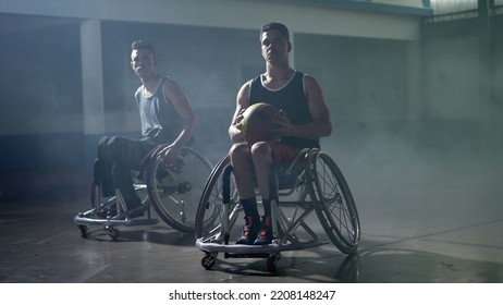 Two Disabled Hispanic Basketball Players In Wheelchairs. Portrait Of A Young South American Man Looking At Camera