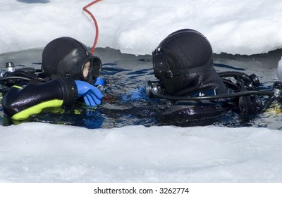 two divers rising on the surface between the ice