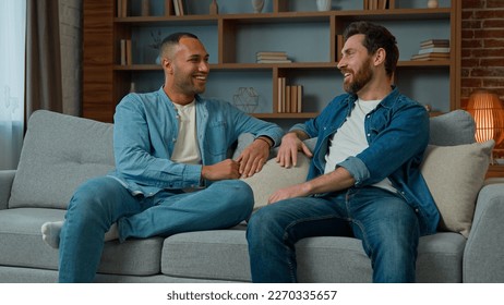 Two diverse 30s men businessmen talking at home on sofa multiracial friends companions african american caucasian ethnicity fellows brothers discussing plans friendly talk male dialogue conversation - Powered by Shutterstock