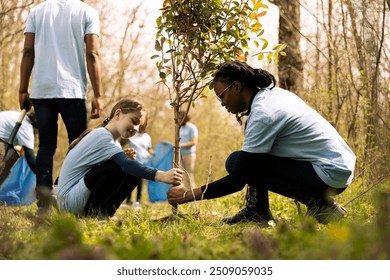 Two diverse activists working together to plant more trees and greenery, filling up ground holes and growing vegetation. Kid and teenager girls collaborating on preserving the environment. - Powered by Shutterstock