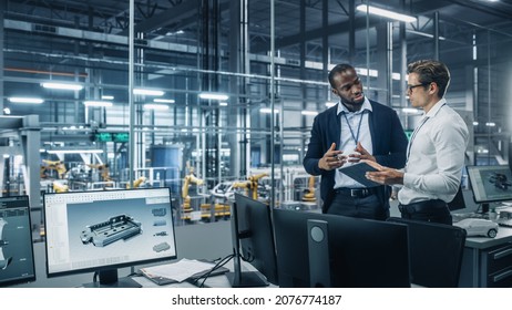 Two Diverse Automotive Industrial Engineers Talking About Vehicle Production while Standing in Office at a Car Assembly Plant. Industrial Specialists Discuss Work Projects on Tablet Computer.