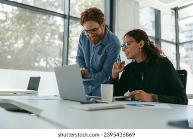 Two diverse business colleagues disscuss biz issue while use laptop in office background - Powered by Shutterstock