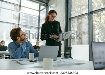 Two diverse business colleagues disscuss biz issue while use laptop in office background