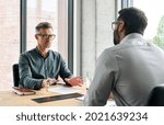 Two diverse business executive partners negotiating at board meeting, manager adviser consulting client discussing financial partnership contract sitting at table in office. Job interview concept.