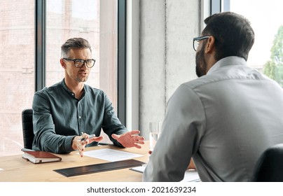 Two diverse business executive partners negotiating at board meeting  manager adviser consulting client discussing financial partnership contract sitting at table in office  Job interview concept 